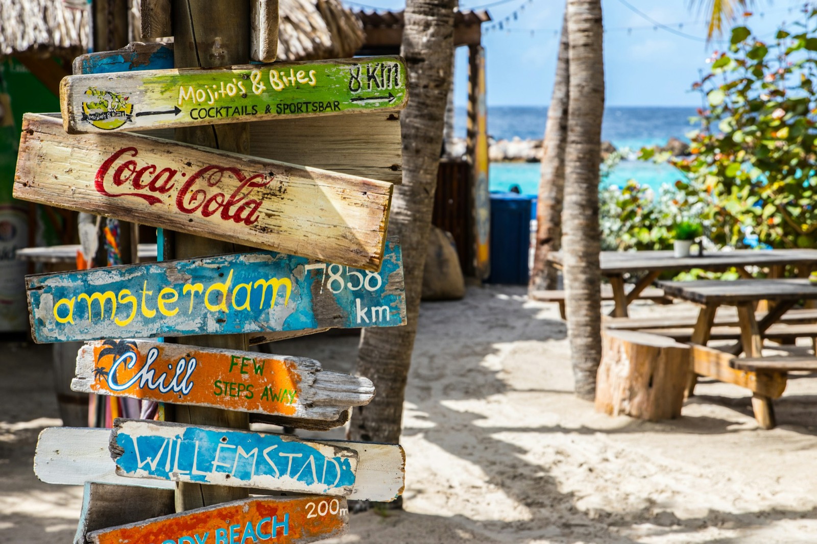 A colourful hand-painted signpost at a Curaçao beach bar