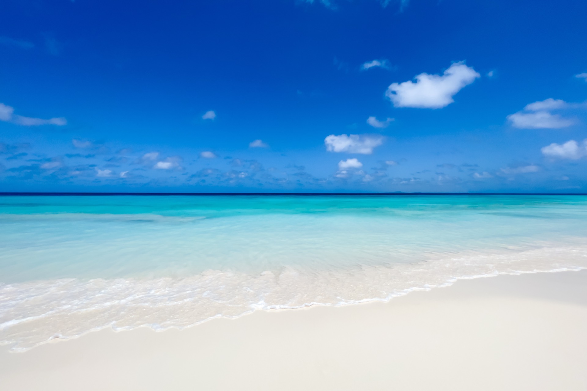 Crystal-clear turquoise water meeting white sand under a blue Caribbean sky